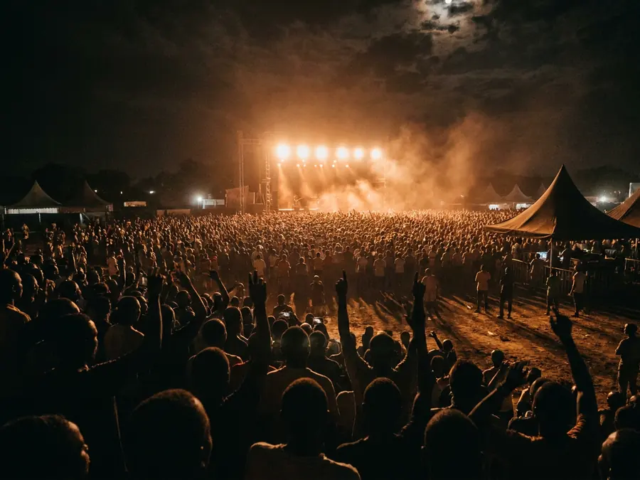 A festival crowd at night in front of a lit stage